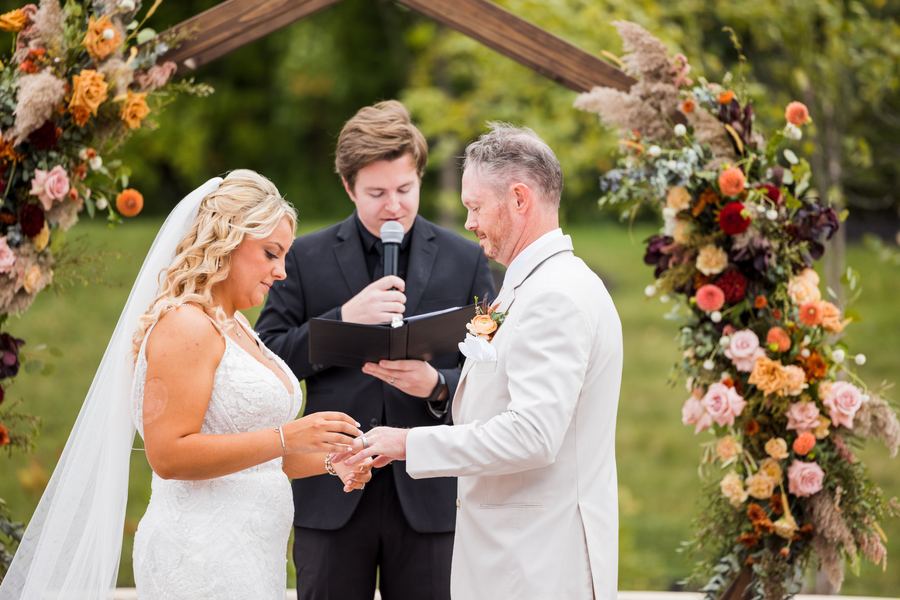 The couple exchanging rings under the floral arch