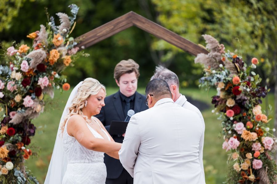 Reed speaking into a microphone between the bride and groom