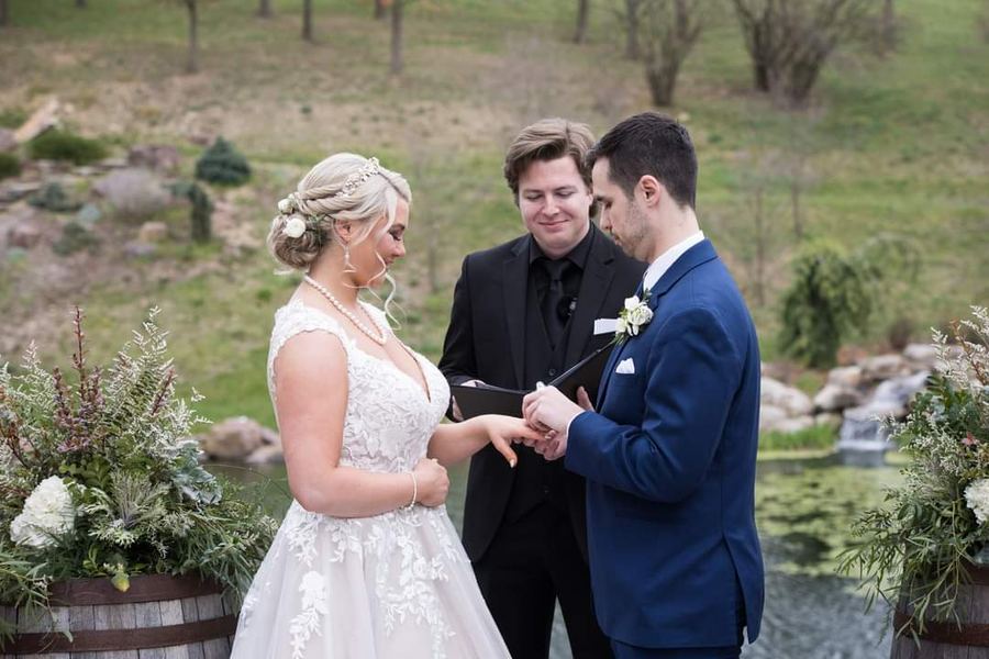 A bride and groom exchanging rings beside a pond