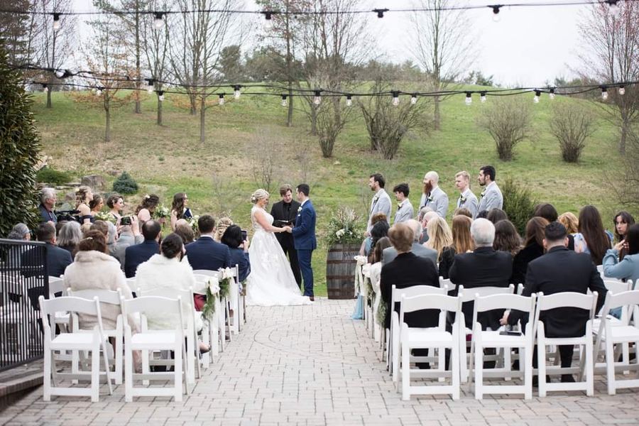 Guests seated outdoors as a couple stands at the front with Reed